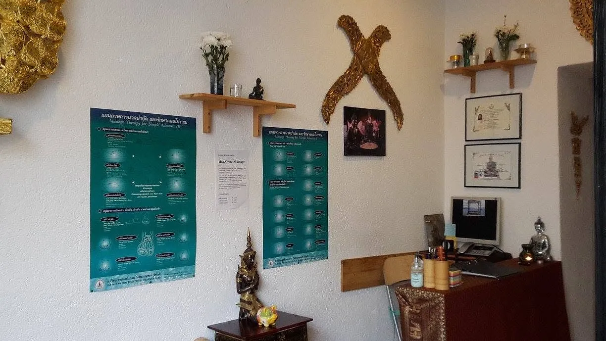 Empfangsbereich mit Buddhafigur, Blumen und thailändischen Informationstafeln